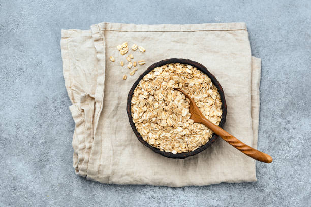 Rolled oats or oat flakes in wooden bowl stock photo