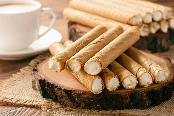 Rolled wafers with whipped cream filling on wooden background. stock photo