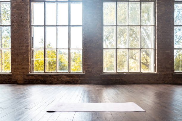 gerollte yoga pilates gummimatte in fitness-studio auf holzboden sport training fitness club klasse trainingsgeräte in reinraum innenraum bieten fenster niemand hintergrundkonzept - loft stock-fotos und bilder