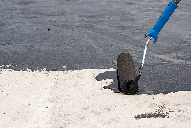Roller brush waterproofing Roofer worker painting black coal tar or bitumen at concrete surface by the roller brush, A waterproofing. tar stock pictures, royalty-free photos & images