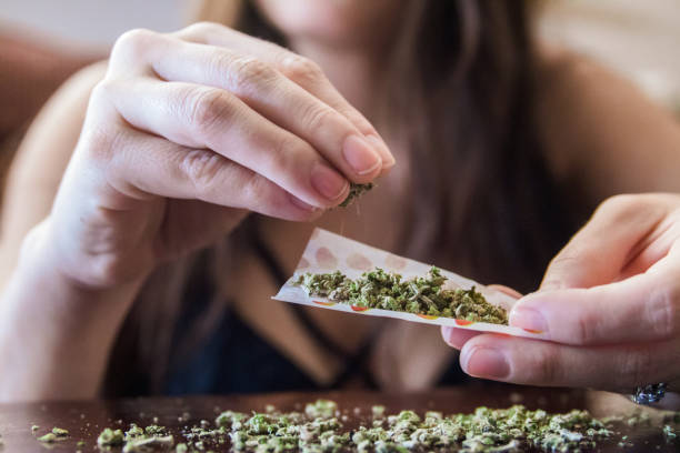Rolling A Joint An anonymous woman placing marijuana flower into a joint paper to smoke. marijuana joint stock pictures, royalty-free photos & images