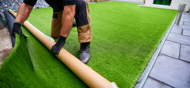 Rolling artificial grass out to fit Installing artificial grass in modern garden of home imitation stock pictures, royalty-free photos & images