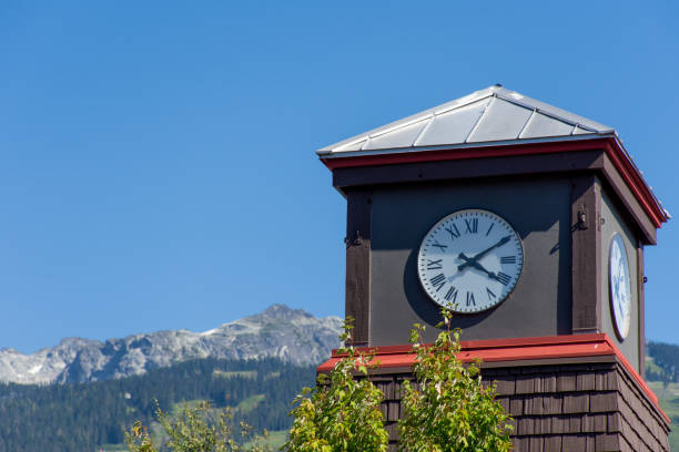 Roman Numeral Clock Tower with rocky mountains and blue sky in the background. stock photo
