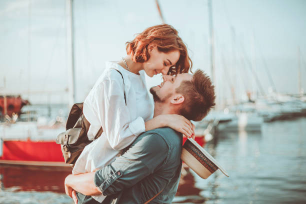 concetto romantico. giovane coppia innamorata in mare su uno sfondo di yachts club. storia amorosa giovanile - couple kiss foto e immagini stock