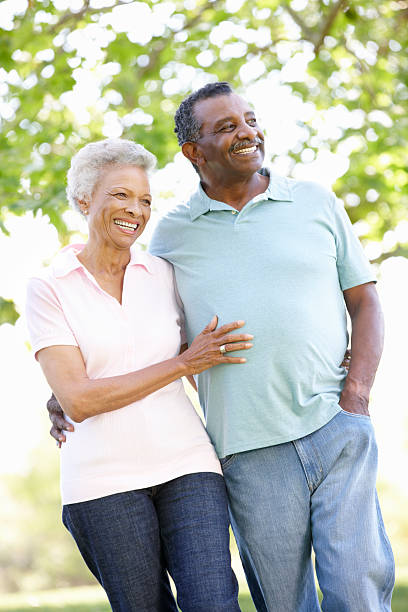Romantic Senior African American Couple Walking In Park Romantic Senior African American Couple Walking In Park And Smiling old black couple in love stock pictures, royalty-free photos & images