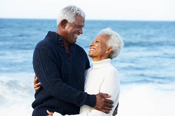 Romantic Senior Couple Hugging On Beach Romantic Senior Couple Hugging On Beach In Daytime Smiling At Each Other old black couple in love stock pictures, royalty-free photos & images