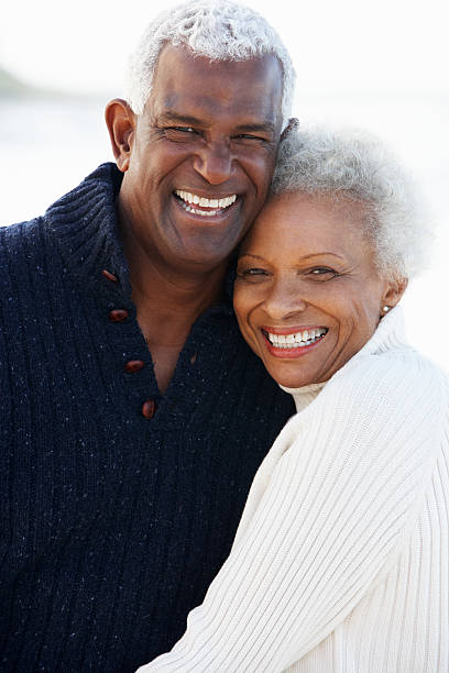 Romantic Senior Couple Hugging On Beach Romantic Senior Couple Hugging On Beach Looking At Camera Smiling old black couple in love stock pictures, royalty-free photos & images