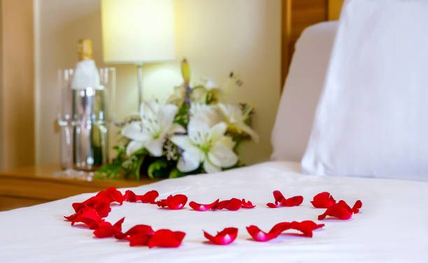 Romantic setup with honeymoon bed with focus on the heart-shaped rose petals stock photo