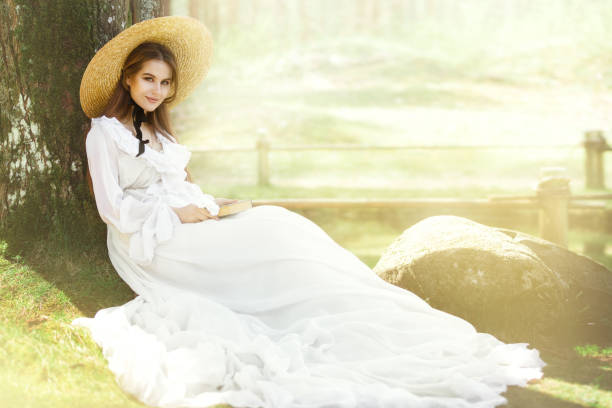 Romantic Woman Victorian Retro Style, Fashion Model in White Dress Hat Reading Book, Outdoor Beauty Portrait Romantic Woman Victorian Retro Style, Fashion Model in White Dress Wide Brim Hat Reading Book, Outdoor Beauty Portrait victorian gown stock pictures, royalty-free photos & images