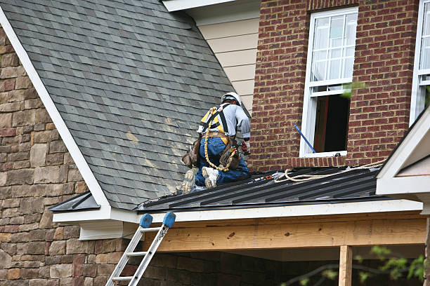 A roofer fixing the roof of a brick house stock photo