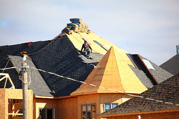 Roofer installing shingles on a new roof stock photo