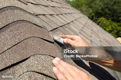 istock Roofer Trimming a New Shingle on Home Construction Project 182911145