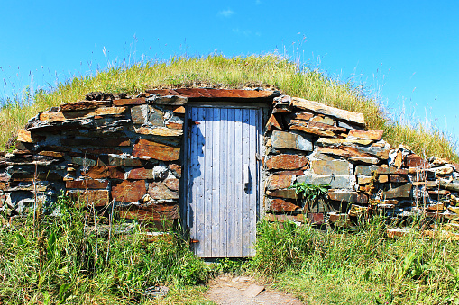 Old stone root cellar with a wooden door, Elliston, Newfoundland.