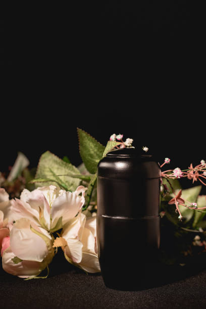 rose bouquet and urn with ashes on black background, funeral concept rose bouquet and urn with ashes on black background, funeral concept funerary urn stock pictures, royalty-free photos & images