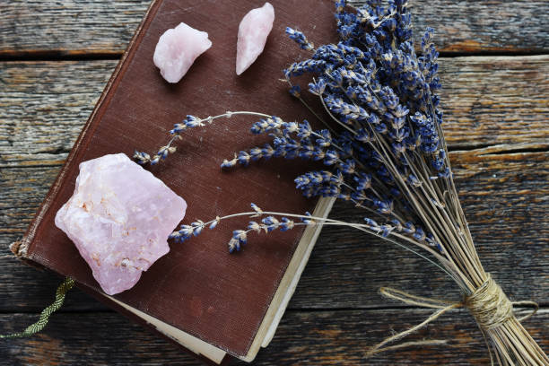 Rose Quartz Crystals A top view image of rose quartz crystals with an old brown book and dried lavender flowers. rose quartz stock pictures, royalty-free photos & images
