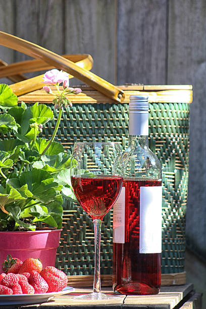 Rose Wine on Wood Table Wine glass and bottle with a picnic basket. In the foreground a plate of strawberries and raspberries. provence rose wine stock pictures, royalty-free photos & images