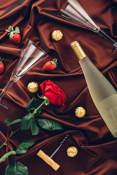 Rose, wine,  petals and strawberry on satin fabric stock photo