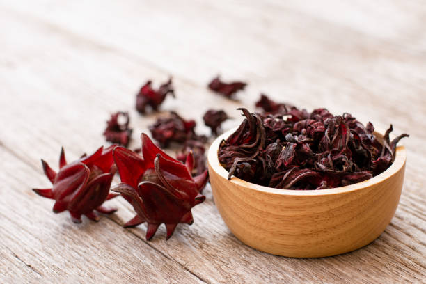 Roselle fruit (Jamaica sorrel, Rozelle or hibiscus sabdariffa) Fresh and dry Roselle fruit (Jamaica sorrel, Rozelle or hibiscus sabdariffa) in wooden bowl isolated on wood table background. hibiscus sabdariffa stock pictures, royalty-free photos & images