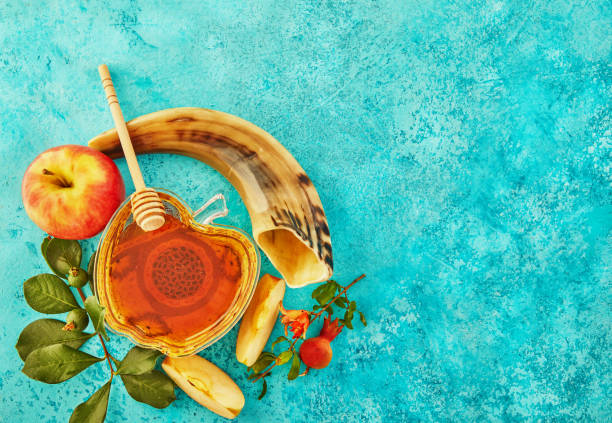 Rosh hashanah - jewish New Year holiday concept. A bowl in the shape of an apple with honey, pomegranate, shofar are traditional symbols of the holiday Rosh hashanah - jewish New Year holiday concept. A bowl in the shape of an apple with honey, pomegranate, shofar are traditional symbols of the holiday. Flat lay honey photos stock pictures, royalty-free photos & images