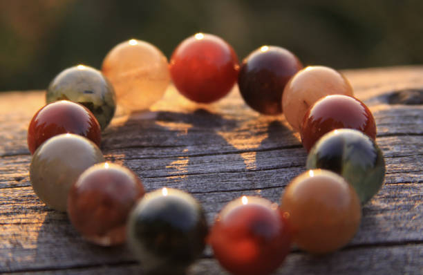 Round gemstone beads in circle on wood shining in sunlight stock photo