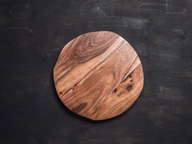 Round wooden tray Round wooden tray or cutting board on black table. Top view of empty kitchen trendy rustic wooden tray saw cut imitation on black wooden background. Copy space for text. Food and menu background. plank timber stock pictures, royalty-free photos & images
