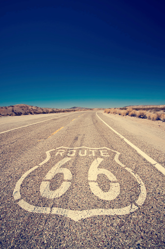 Vintage effect on Route 66 and its famous sign painted on the road - Arizona