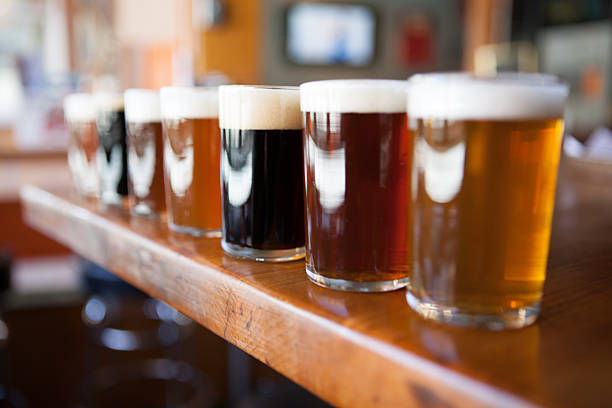 Row of different beers in glasses on a wooden bar stock photo