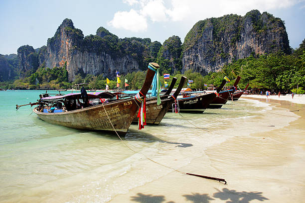 Row of longtail boats against background of cliffs in Thailand stock photo