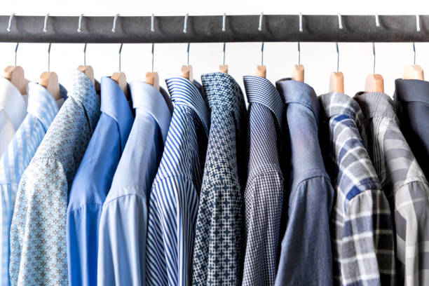 Row of men's shirts in blue colors on hanger Row of men's shirts in blue colors on hanger on white background button down shirt stock pictures, royalty-free photos & images
