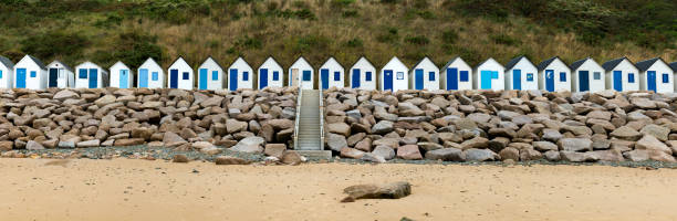 row of small wooden beach cottages on the rocky Normandy coast Carteret, Normandy / France:- 17 August, 2019: colorful row of small wooden beach cottages on the rocky Normandy coast in Barneville-Carteret barneville carteret photos stock pictures, royalty-free photos & images