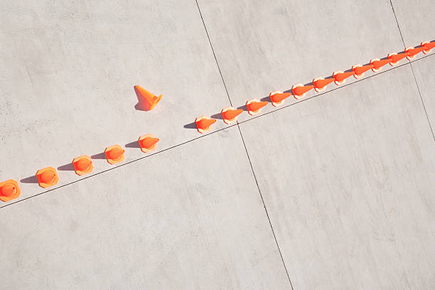 row of traffic cones with one on side - onvolkomenheid stockfoto's en -beelden