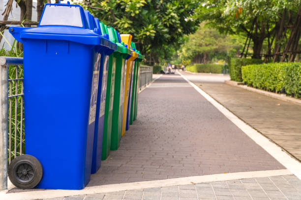 Row of Wheelie Bins. Many trash carts set in the park. There are blue, green and yellow tanks. Copy space. stock photo