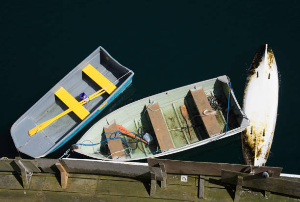 Rowboats at the Dock Two rowboats and a canoe that is capsized are moored to a floating dock. capsizing stock pictures, royalty-free photos & images