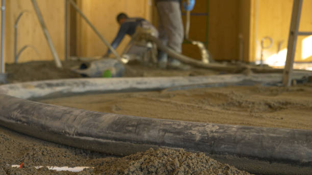 CLOSE UP: Rubber hose pulsates as contractors pour concrete across the ground. stock photo