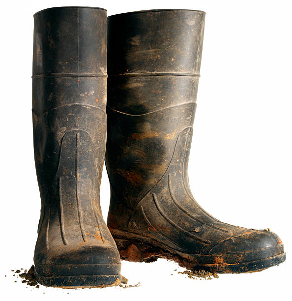 Rubber Work Boot, Isolated Hard working black rubber boots covered in dirt against a white background. burwellphotography stock pictures, royalty-free photos & images