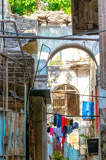 Havana, Cuba - May 15, 2022: Run-down architecture of a community style known in the capital city as 'solar' o 'solares'. The traditional clothesline and water storage tank are seen in the house.