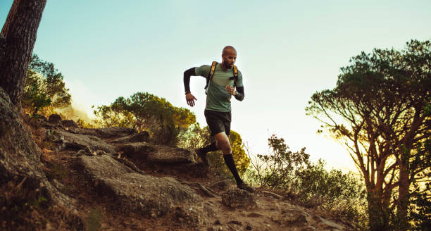 Runner running through rocky mountain path Man running on mountain trail. Fitness male running through rocky mountain path. cross country running stock pictures, royalty-free photos & images