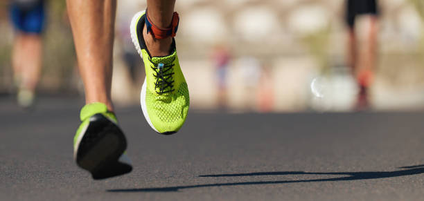 Runners feet running on road close up on shoe Runners feet running on road close up on shoe, male triathlete runner marathon stock pictures, royalty-free photos & images