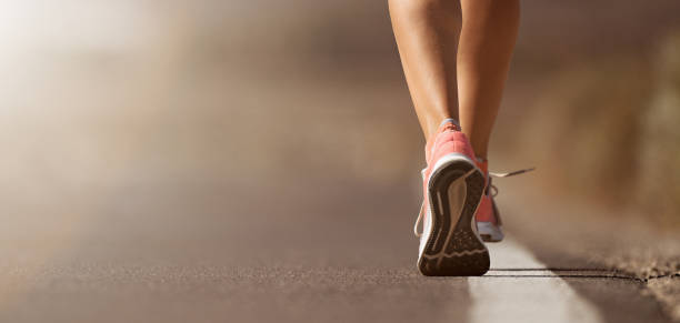 running shoe closeup of woman running on road - pes imagens e fotografias de stock