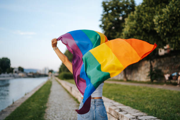 Running with pride Young  lesbian woman with rainbow flag running on city quay lgbtqia people stock pictures, royalty-free photos & images