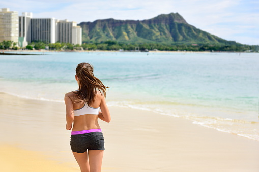 Running woman runner jogging on beach run. Female athlete fitness runner jogger training living healthy active exercise lifestyle exercising outdoor on Waikiki Beach, Honolulu, Oahu, Hawaii, USA.