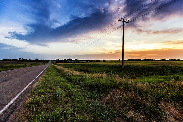Rural Kansas Highway Morning Sunrise Diminishing perspective scenic view of a long, straight, rural Kansas, USA highway just after sunrise early on a crisp summer morning. telephone pole photos stock pictures, royalty-free photos & images