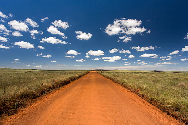 Rural orange dirt road with blue sky and far horizon stock photo