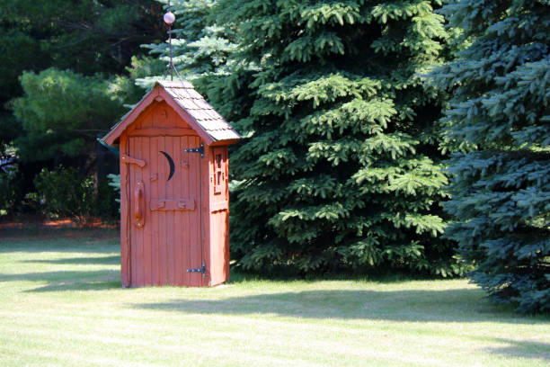 rural red outhouse privy toilet building forest glade stock photo