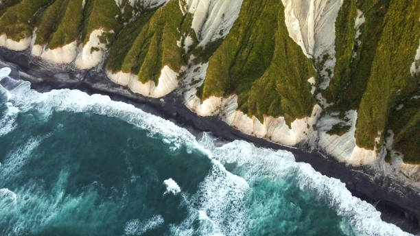 Russia, Kuril Islands, Iturup Island, White rocks on coast of the Sea of Okhotsk. Aerial. stock photo