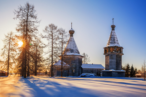 Old Russian wooden church of the Epiphany with a bell tower in the village Oshevensk, Arkhangelsk region, Russia. Winter morning rural landscape