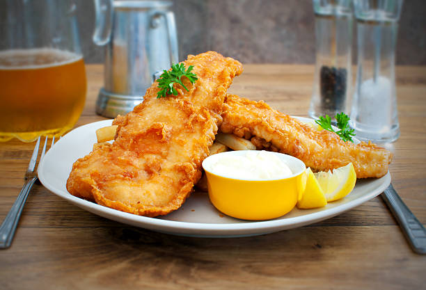 Rustic fish and chips Two pieces of deep fried fish with chips on a plate fried fish stock pictures, royalty-free photos & images