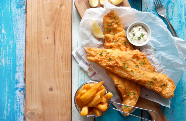 Rustic fish and chips Traditional British fried fish in batter with chips in a basket fried fish stock pictures, royalty-free photos & images