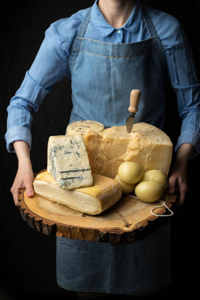 rustico formaggio gourmet italiano su tavola di legno in mani di casaro su sfondo nero - asolani foto e immagini stock