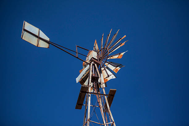 Rusty old farm windmill against blue sky stock photo